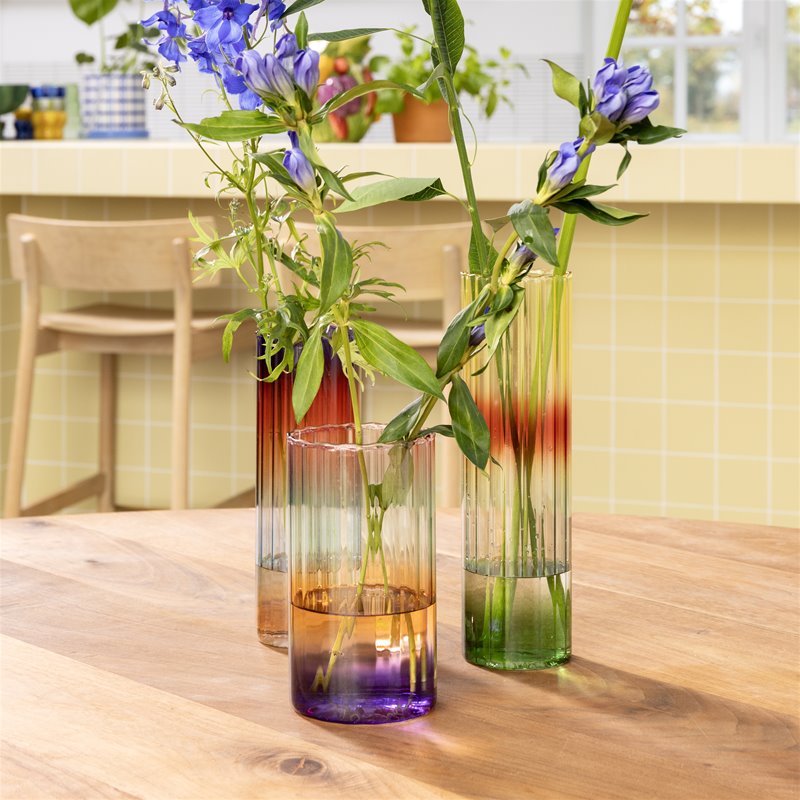 tall gradient glass vases by &k styled with flowers on a wooden table
