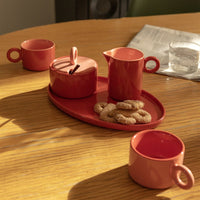 red chiquito stoneware tray with matching mugs styled for a cosy coffee moment
