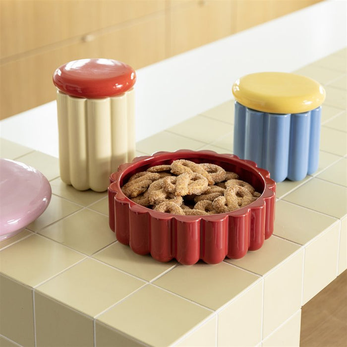 Colorful cookie jars by &klevering on a tiled kitchen counter with cookies inside one of them.