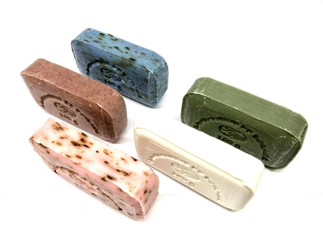 Five different colored and naturally scented soap bars on a white background
