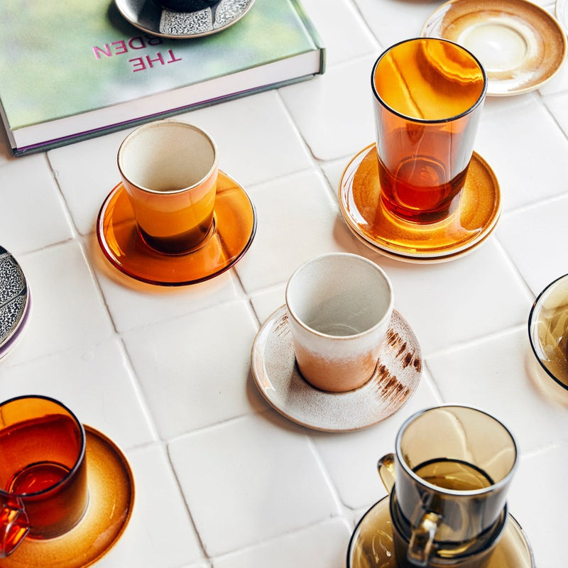 hkliving saucers and cups in an arrangement on a table with brown glass saucers and mugs, as well as stoneware cups and suacers