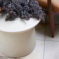 large earthenware cream white accent table with large bunches of berries on a tiled floor next to a mid century chair in the nordic style of hkliving design house