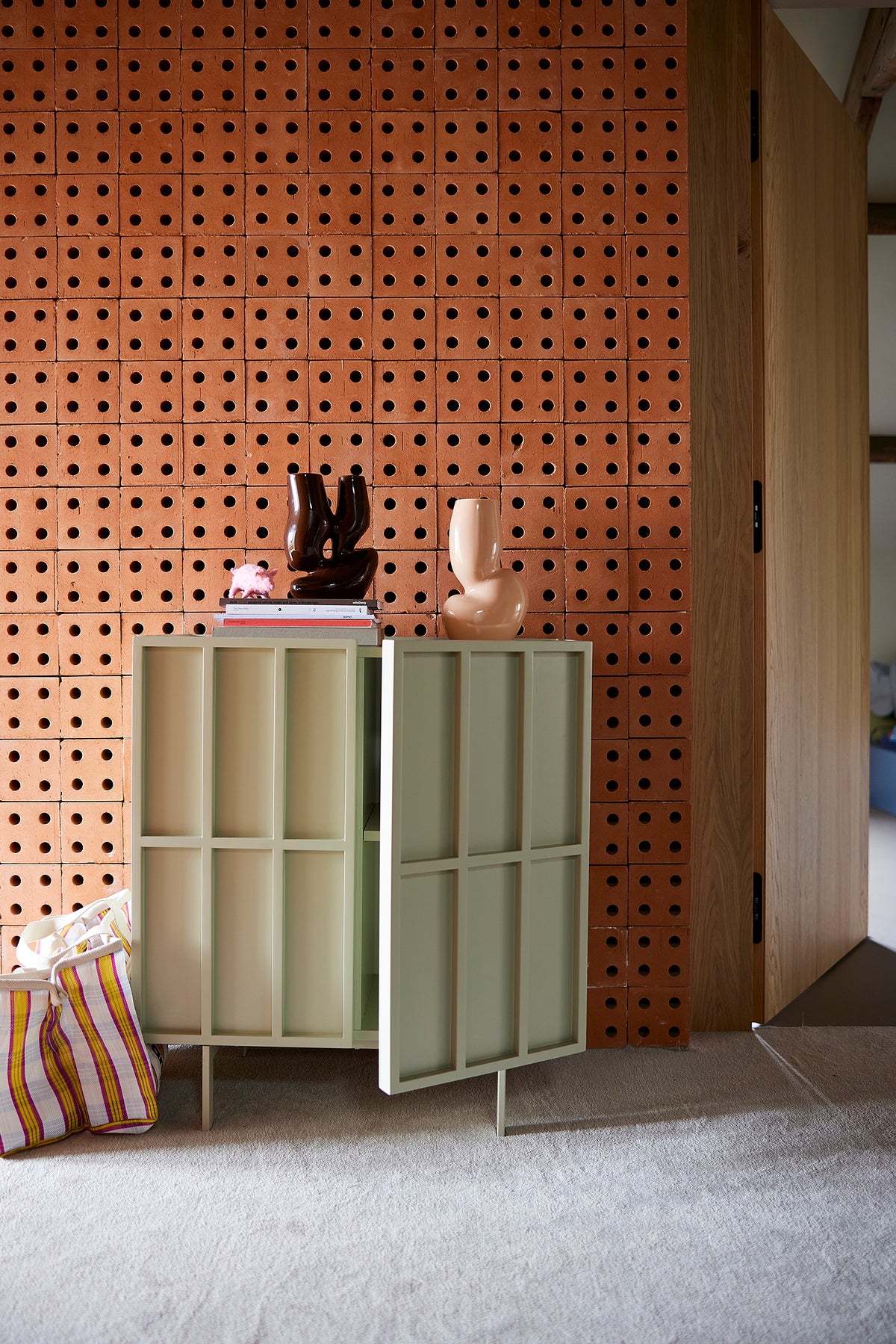 Cream HKLIVING block cupboard with one door ajar, styled against a terracotta pegboard wall
