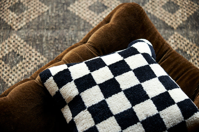 fluffy black and white chequered woolen cushion on a sofa in a scandi style from hk living