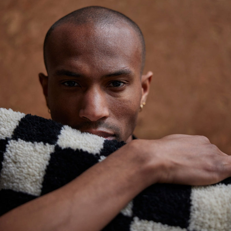 cute guy holding on tight to the fluffy black and white cushion from nordic design studio hkliving