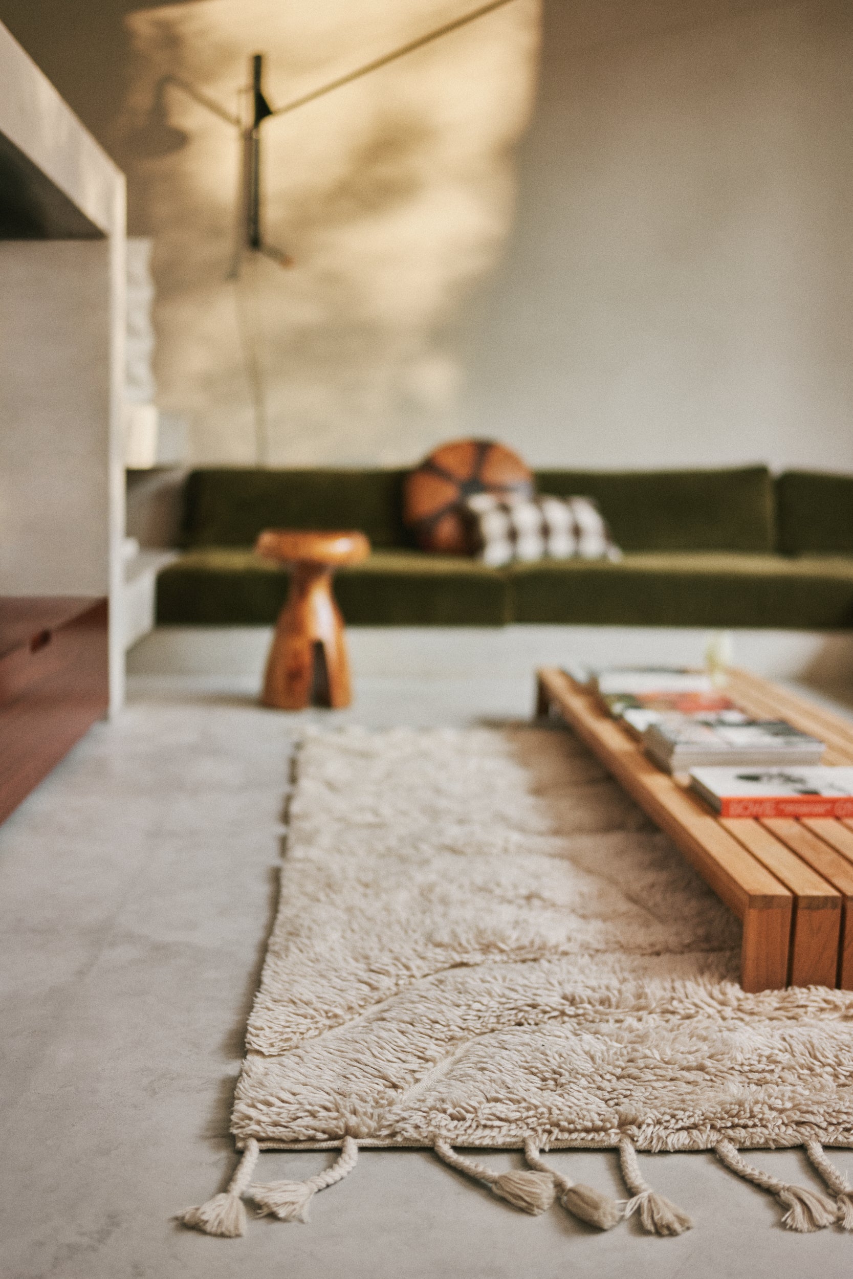 HKLIVING wool rug limitless in cream styled in an entryway with an orange striped lounge chair and low shelving unit