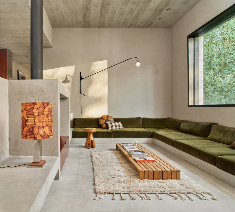 HKLIVING wool rug limitless in cream in a living room setting with a green corner sofa, wooden stool and table lamp