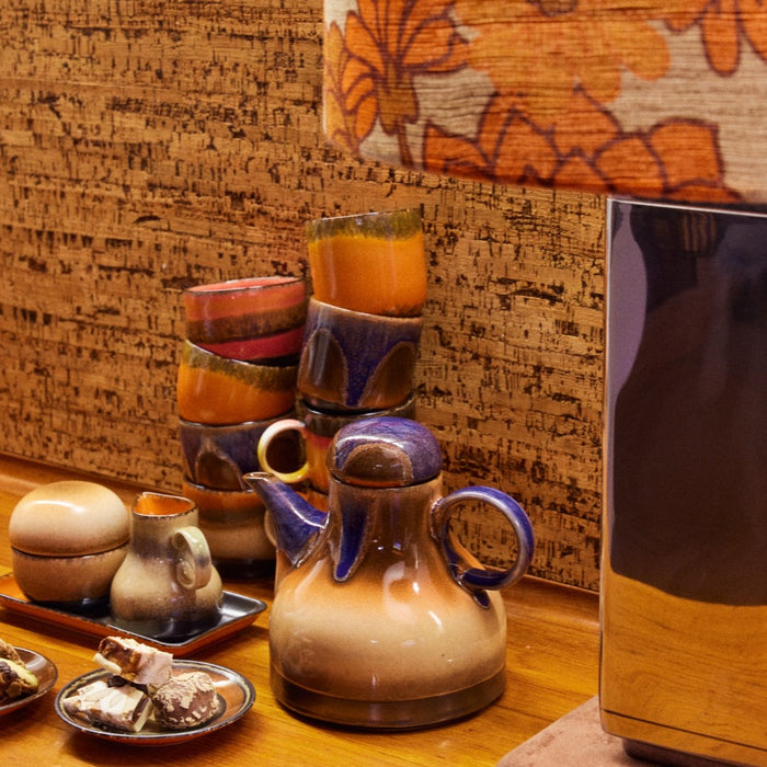 collection of 70s ceramics from hliving on a wooden sideboard including a coffee pot and cups and mugs in theis 70s style bringing style colour and drama to an afternoon tea