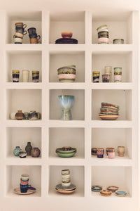 Shelving unit with various ceramic items including cups, bowls, and vases from HKLIVING 70s Collection.