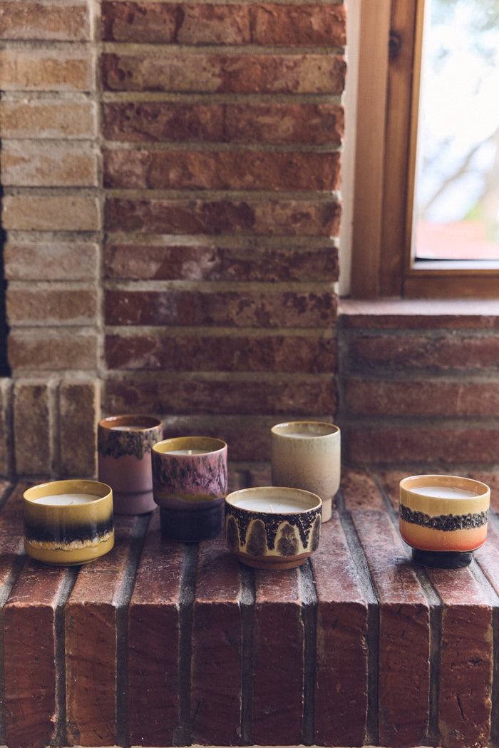 Collection of HKLIVING ceramic candles on a brick surface with a brick wall and window in the background