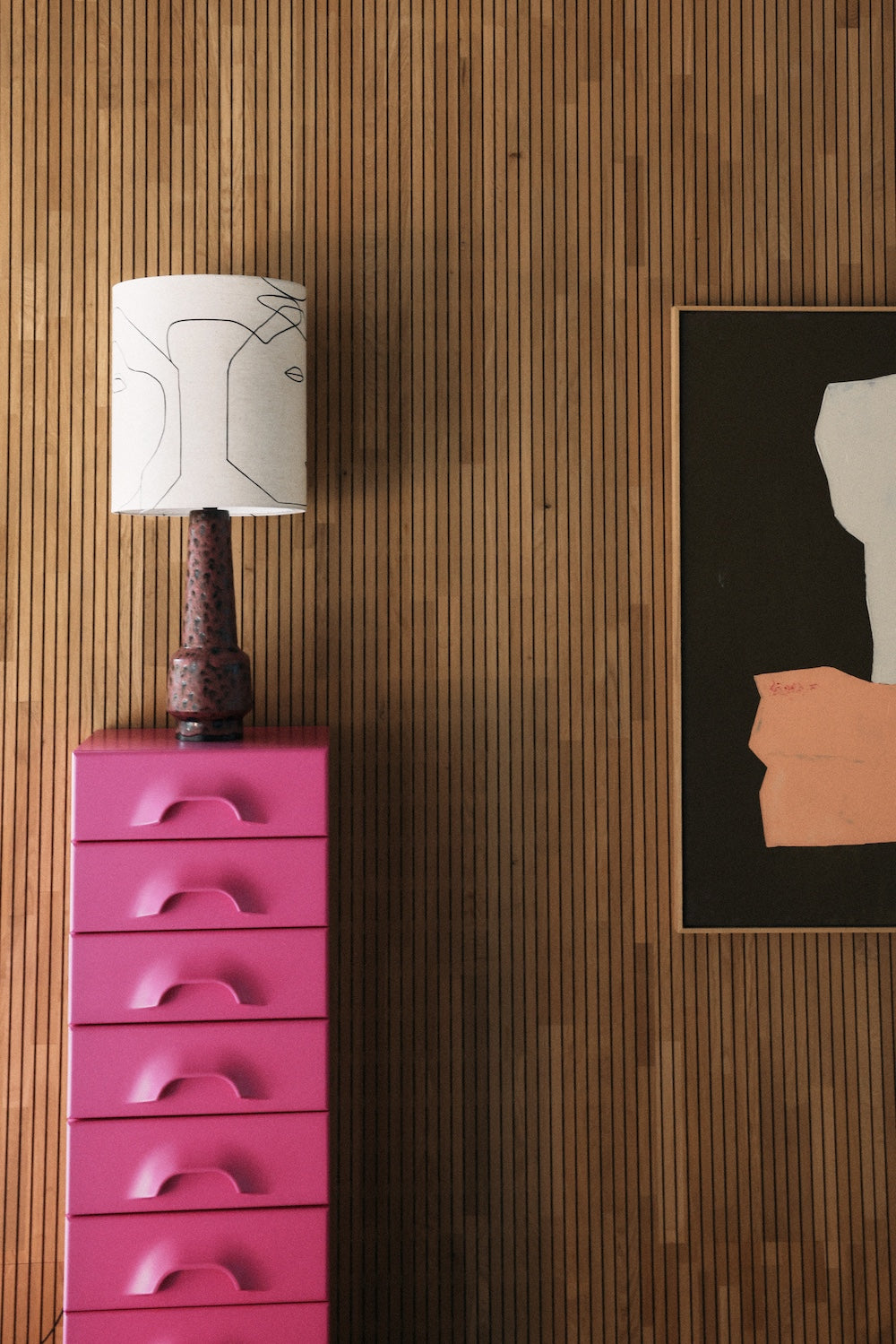 HKLIVING printed faces lamp shade styled on a bedside table beside a pink chest of drawers and framed artwork