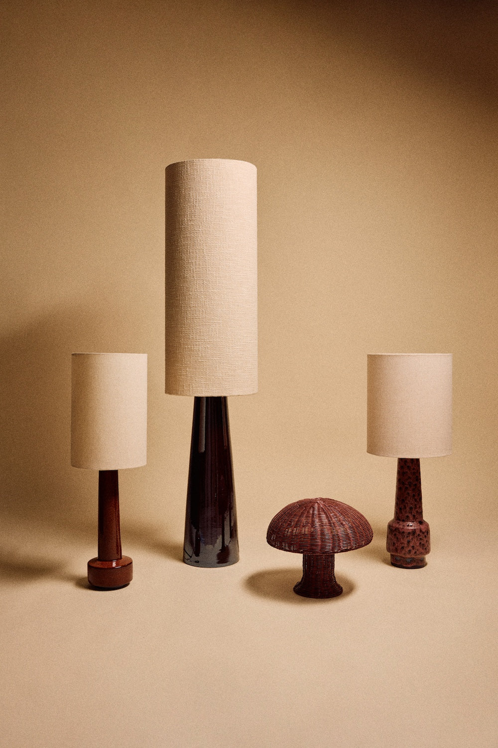 group of HKLIVING table lamps with natural linen shades on glazed stoneware bases, beside a woven rattan mushroom lamp