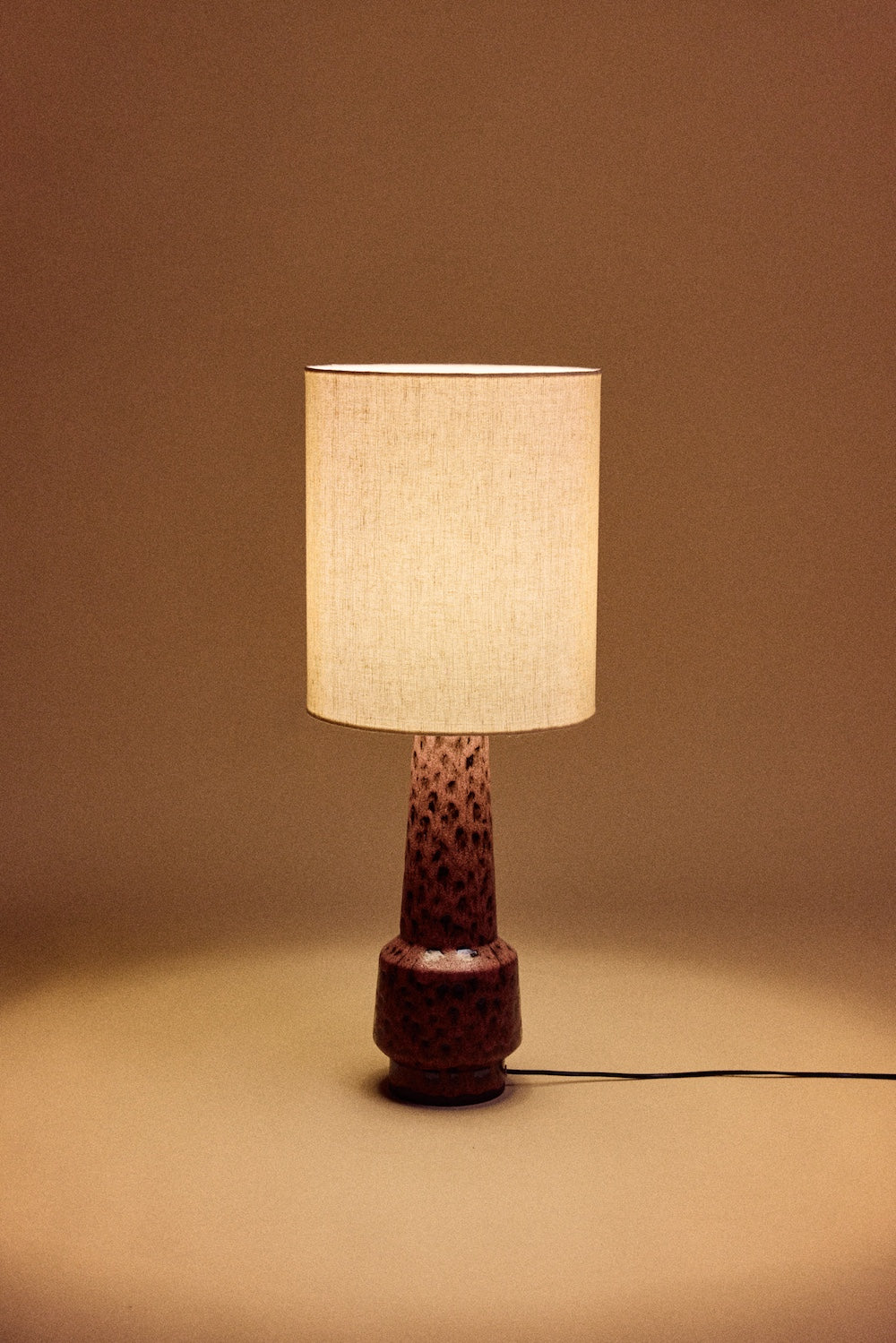 HKLIVING natural linen cylinder lamp shade lit and glowing on a maroon speckled ceramic base