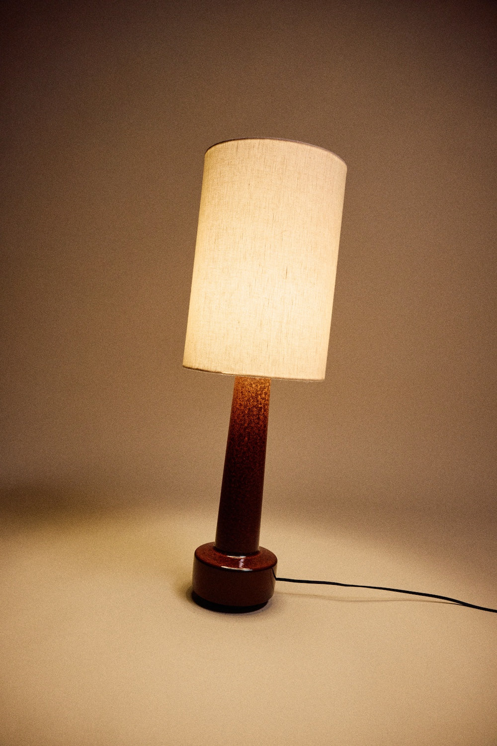 HKLIVING table lamp with natural linen shade and glazed brown stoneware base, lit against a warm brown backdrop