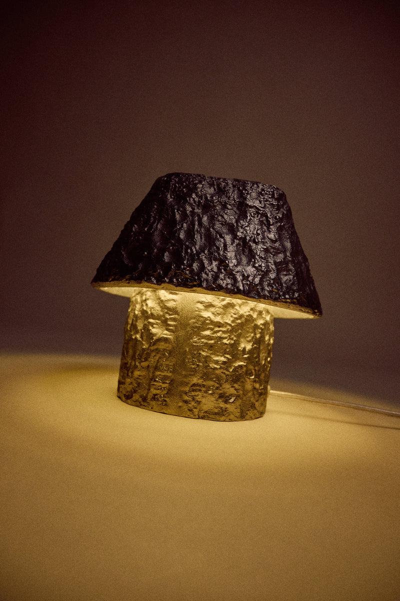 textured aluminium mushroom lamp glowing warmly in a dark room by hkliving