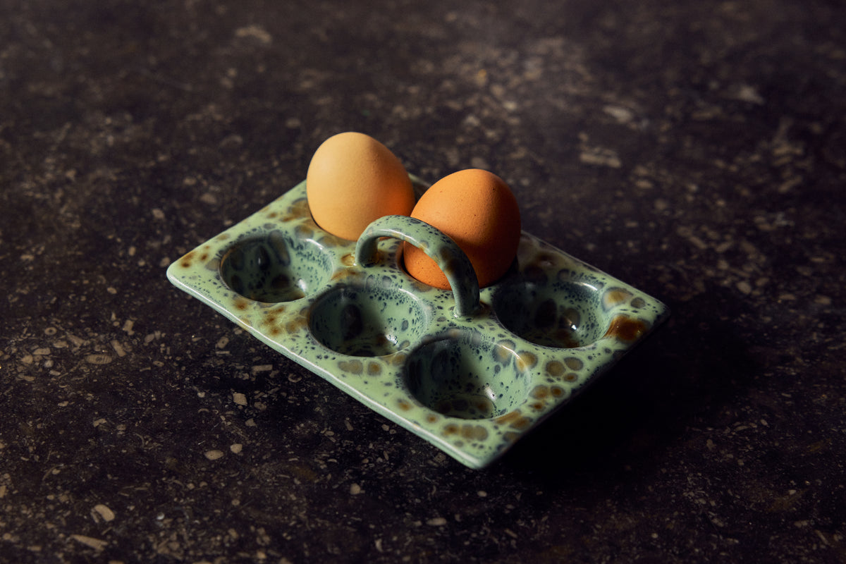 70s Ceramics Egg Tray in Minty holding two boiled eggs, shown close up on a dark surface