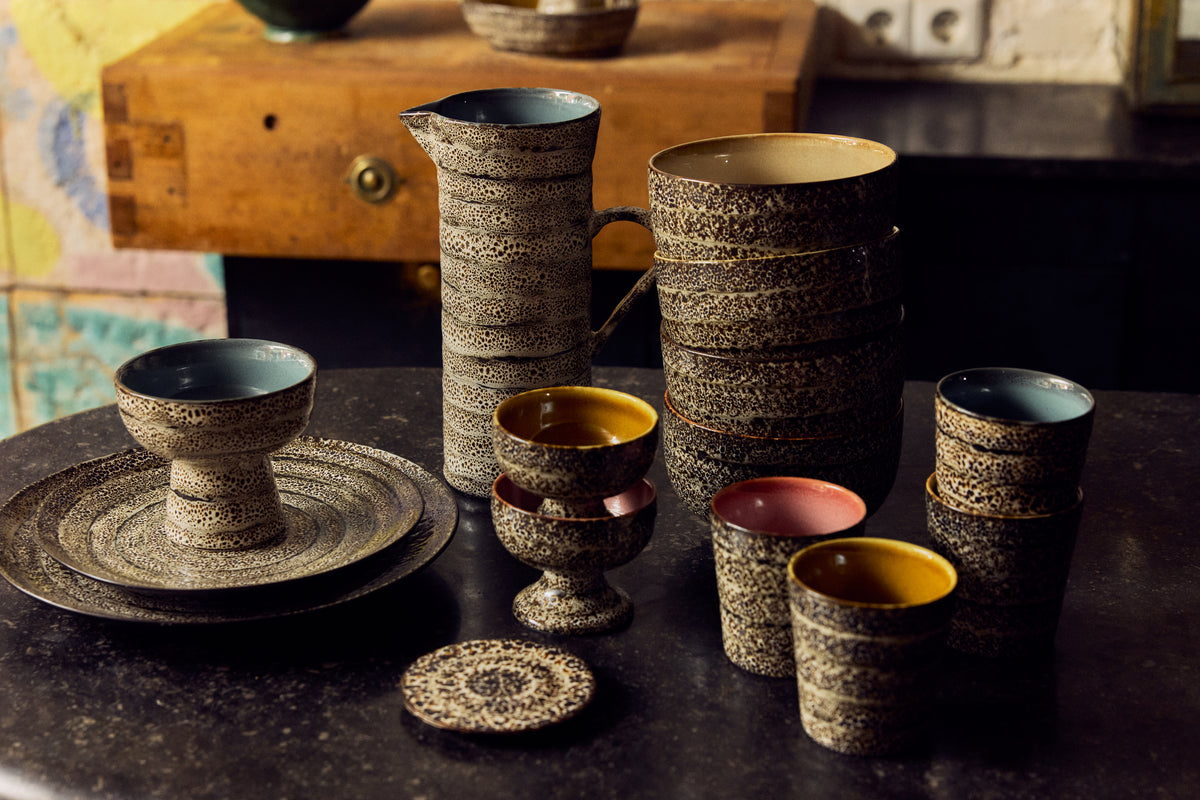 70s Ceramics Jug in Brew displayed on open shelving alongside speckled bowls, plates and a red jug from the wider 70s Ceramics range