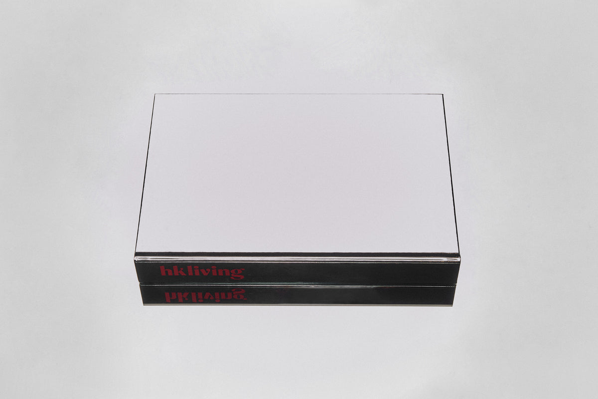 HKLIVING Limited Edition Lookbook 2026-2027 styled on a wooden coffee table alongside other design books, a metal sculptural object and ceramic plates
