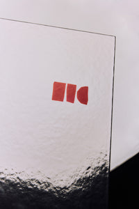 Close-up detail of the HKLIVING Limited Edition Lookbook 2026-2027 cover corner, showing the red logo mark and the cover's reflective gradient finish