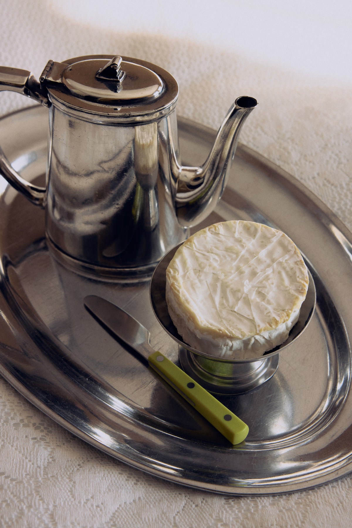 Silver tray with a teapot, a round cheese and an HKLIVING lemon butter knife
