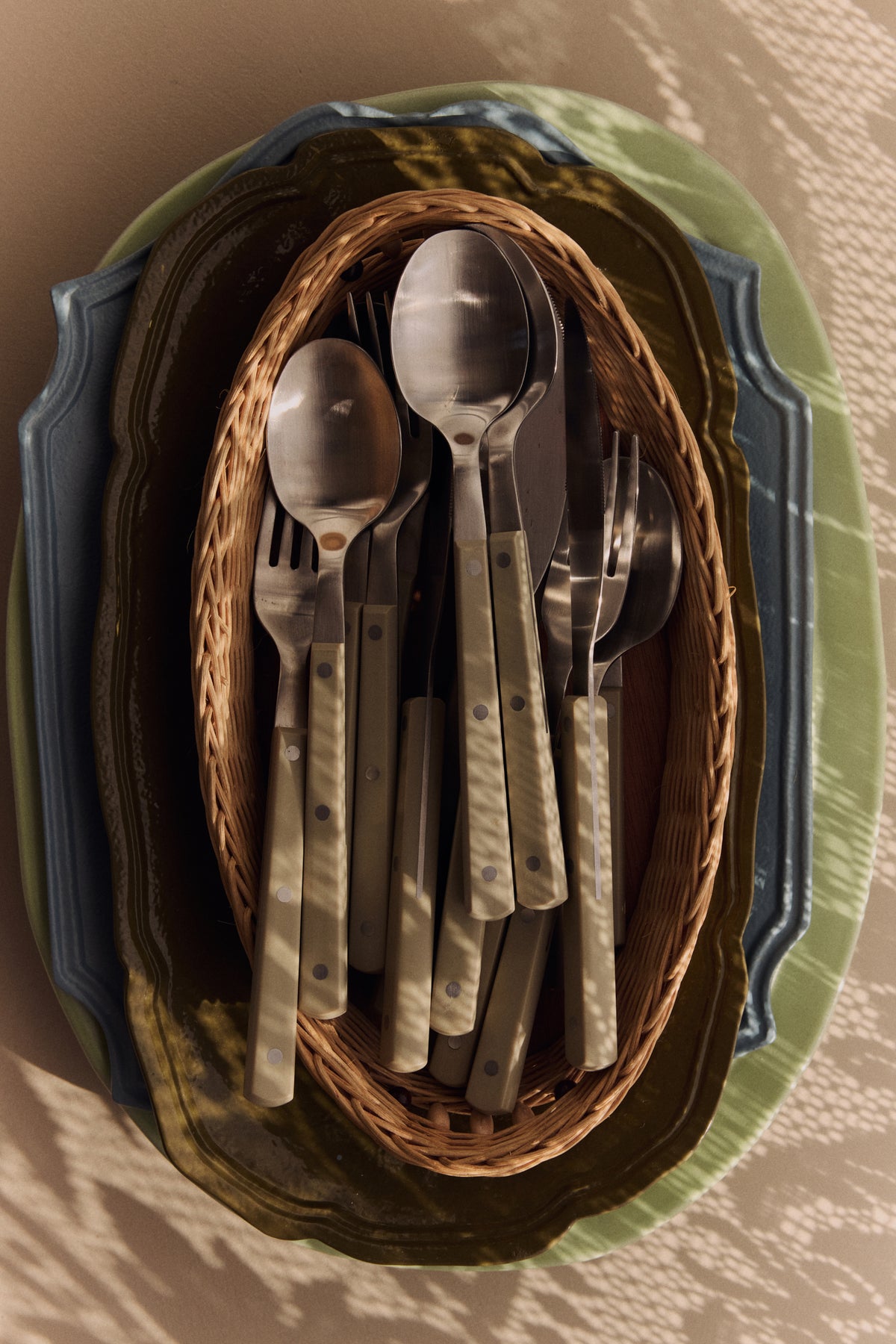 HKLIVING olive 70s Cutlery gathered in a woven rattan basket on a green scalloped plate