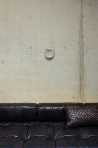 HKLIVING Dent Wall Sculpture in Overcast mounted on a concrete wall above a dark leather sofa