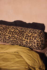 Close-up of HKLIVING leopard print bolster cushion on a bed with mustard yellow and brown bedding