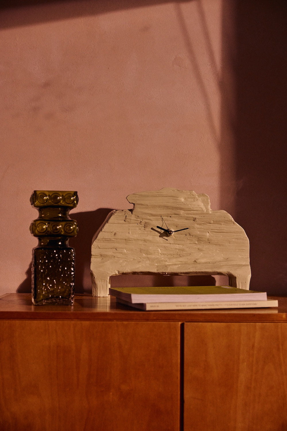 The HKLIVING seafoam mantle clock displayed on a wooden sideboard next to a dark green ribbed glass candlestick, styled on a magazine against a soft pink wall
