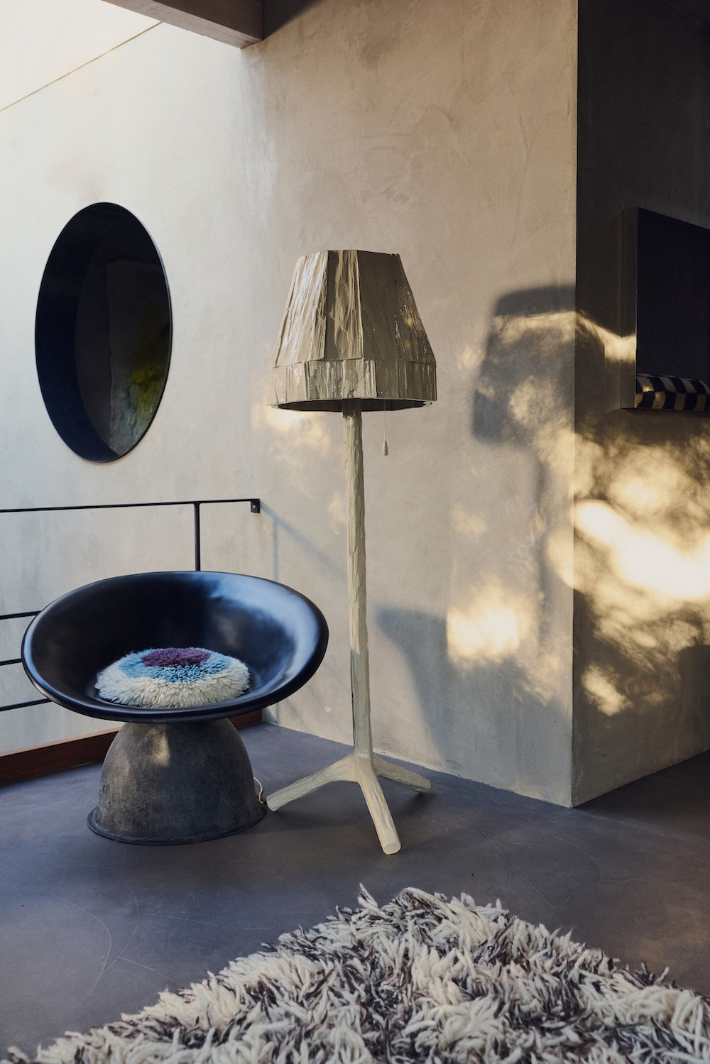 Teun Zwets for HKLIVING Overcast floor lamp styled beside a black leather chair and shaggy rug in a plastered interior
