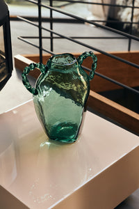 Close-up of green glass amphora vase styled on a console table