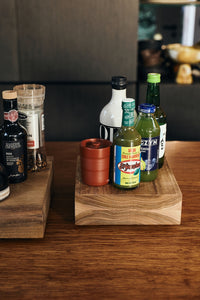 Bottles of oil, vinegar and condiments arranged on top of the medium HKLIVING teak cube, styled next to a second wooden riser on a kitchen counter