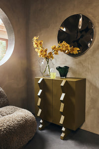HKLIVING emerald green folded vase styled with a clear glass vase of yellow orchids on an olive green cabinet
