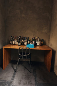 HKLIVING Pop Cube Large in Blue on a timber desk alongside spirits bottles against a dark plaster wall