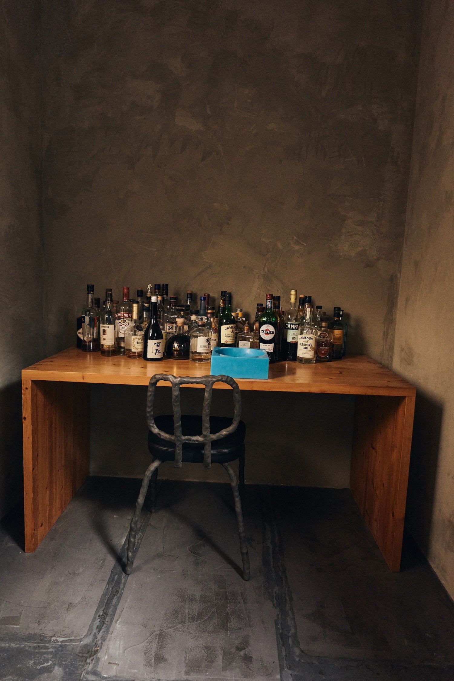 HKLIVING Pop Cube Large in Blue on a timber desk alongside spirits bottles against a dark plaster wall