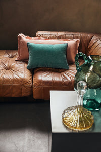 Dusty peach linen cushion styled with a green velvet cushion on a leather sofa
