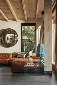 Teun Zwets for HKLIVING Sky Blue table lamp styled on a glass side table beside a leather sofa