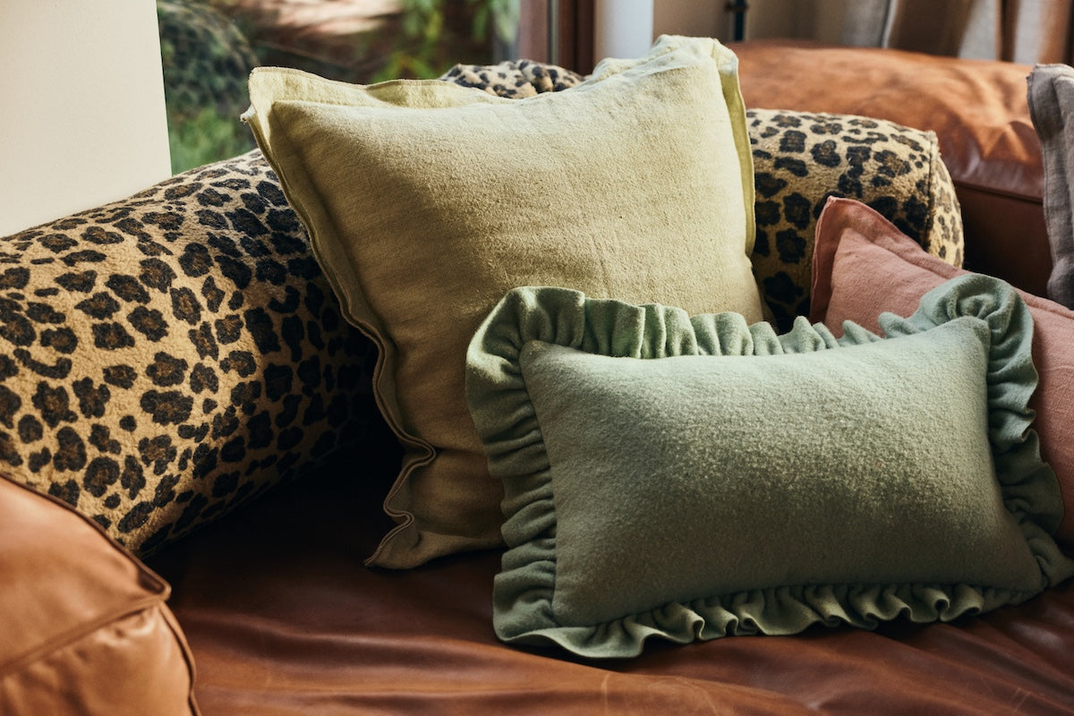 Close-up of HKLIVING mint felt cushion with ruffled edge styled against leopard print and terracotta cushions on a leather sofa