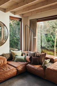 Leather sectional sofa styled with leopard print bolster cushions and an assortment of linen scatter cushions