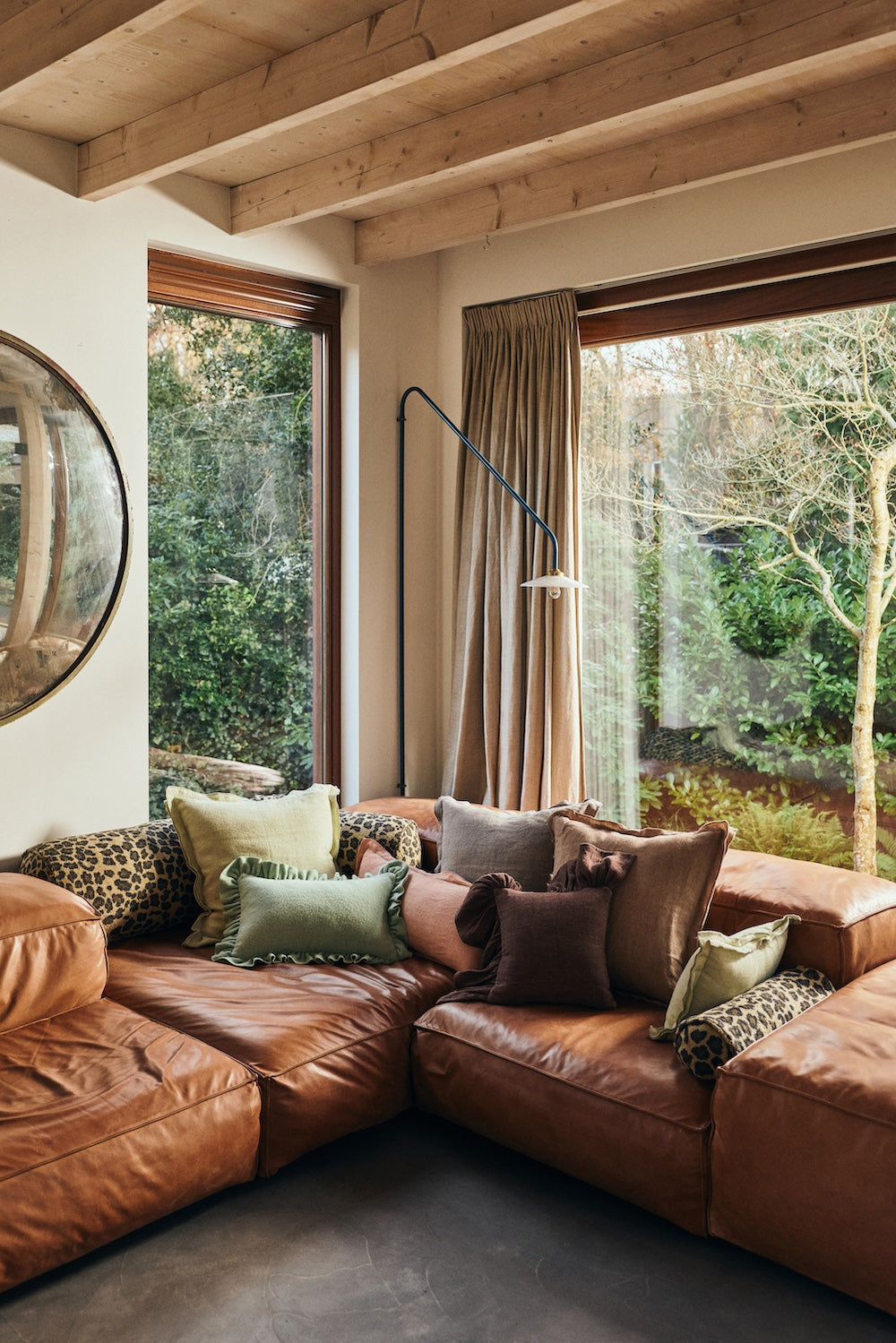 Leather corner sofa in a bright living room styled with an assortment of cushions, including the HKLIVING Panther bolster in leopard print
