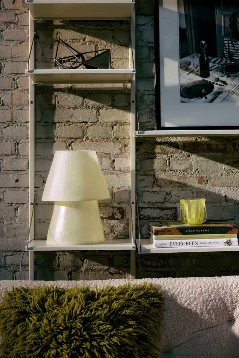 HKLIVING Glassfibre Table Lamp in Off White on a wall-mounted shelf alongside books and a moss green cushion