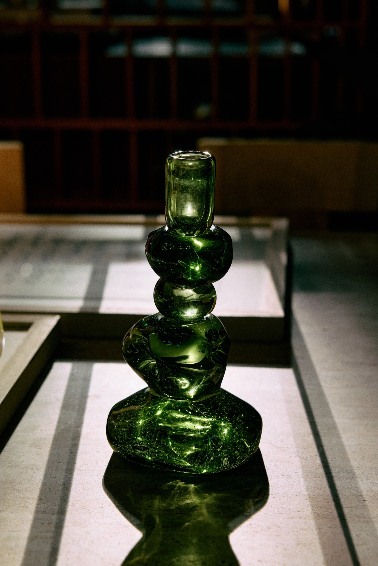 Emerald glass candle holder styled in a dimly lit interior, catching ambient light