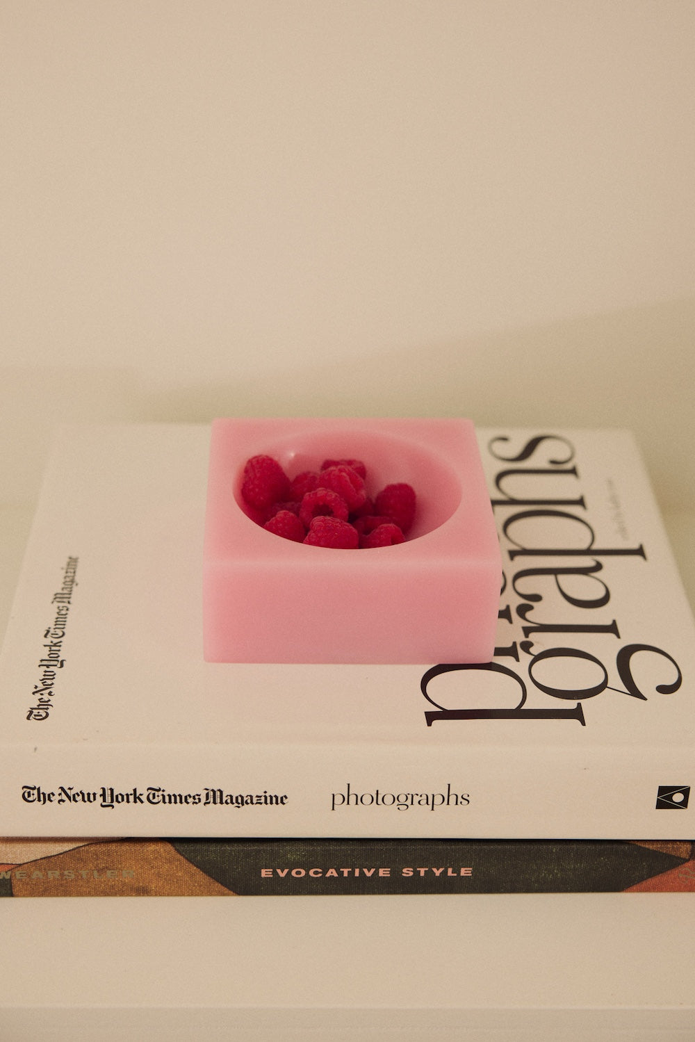 The HKLIVING Pop Cube Small in Pink filled with raspberries, resting on a stack of coffee table books