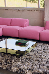 HKLIVING Acrylic Coffee Table in olive in front of a pink modular sofa, with a book resting on the mirrored top