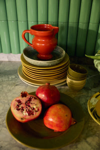 HKLIVING Farmhouse Ceramics small jug in red displayed on a stack of plates in a green-tiled kitchen, styled with fresh pomegranates