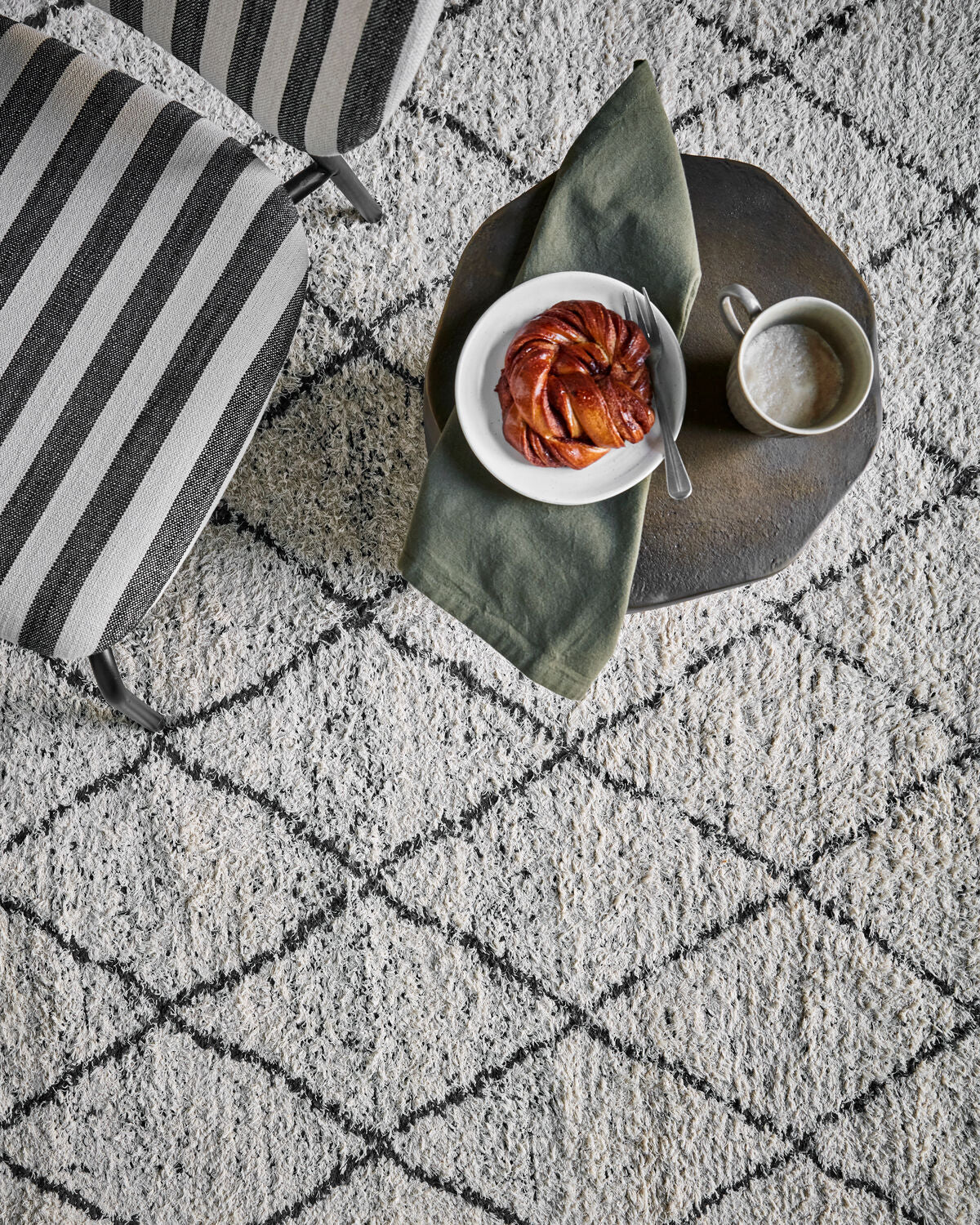 House Doctor Cruz reversible rug styled overhead with coffee tray and striped cushion