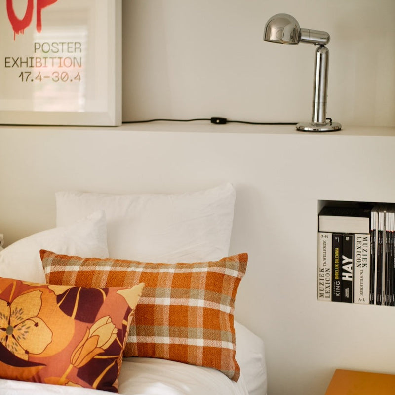 bed spread with chequered cushions from hklving with a table lamp and side table