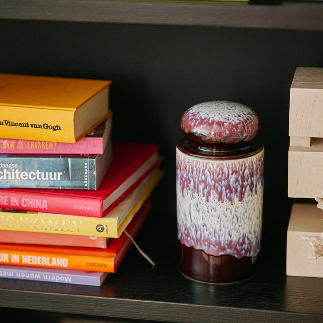 purple, blue, and white lidded storage jar on a shelf with books and an art piece from hkliving in 70s colours and joyful style