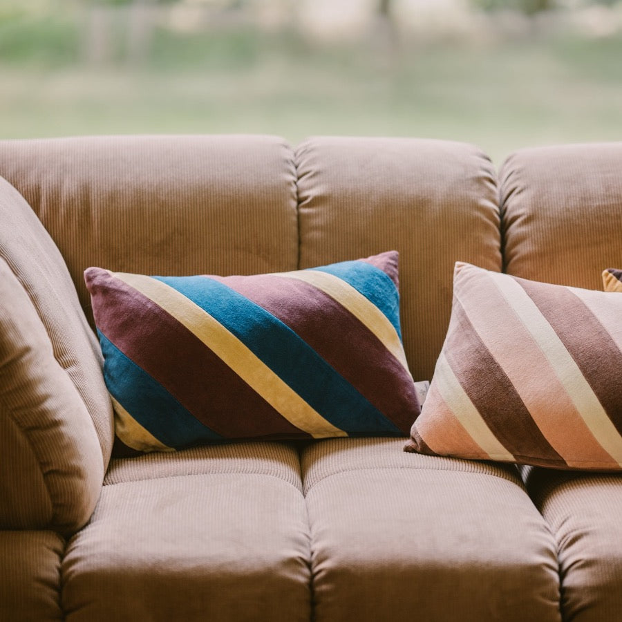 gorgeous pink cordurouy sofa with diagnoally striped cushions with blue, purple, and beige from hkliving