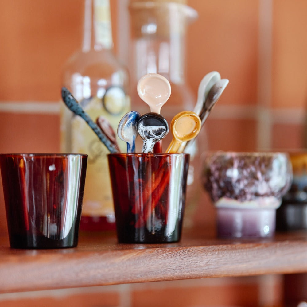 ceramic spoons stood in a red glass tumbler next to other hkliving mugs