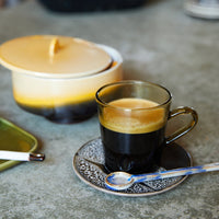 ceramic spoon on a 70s ceramic saucer from hkliving and a brown glass coffee mug